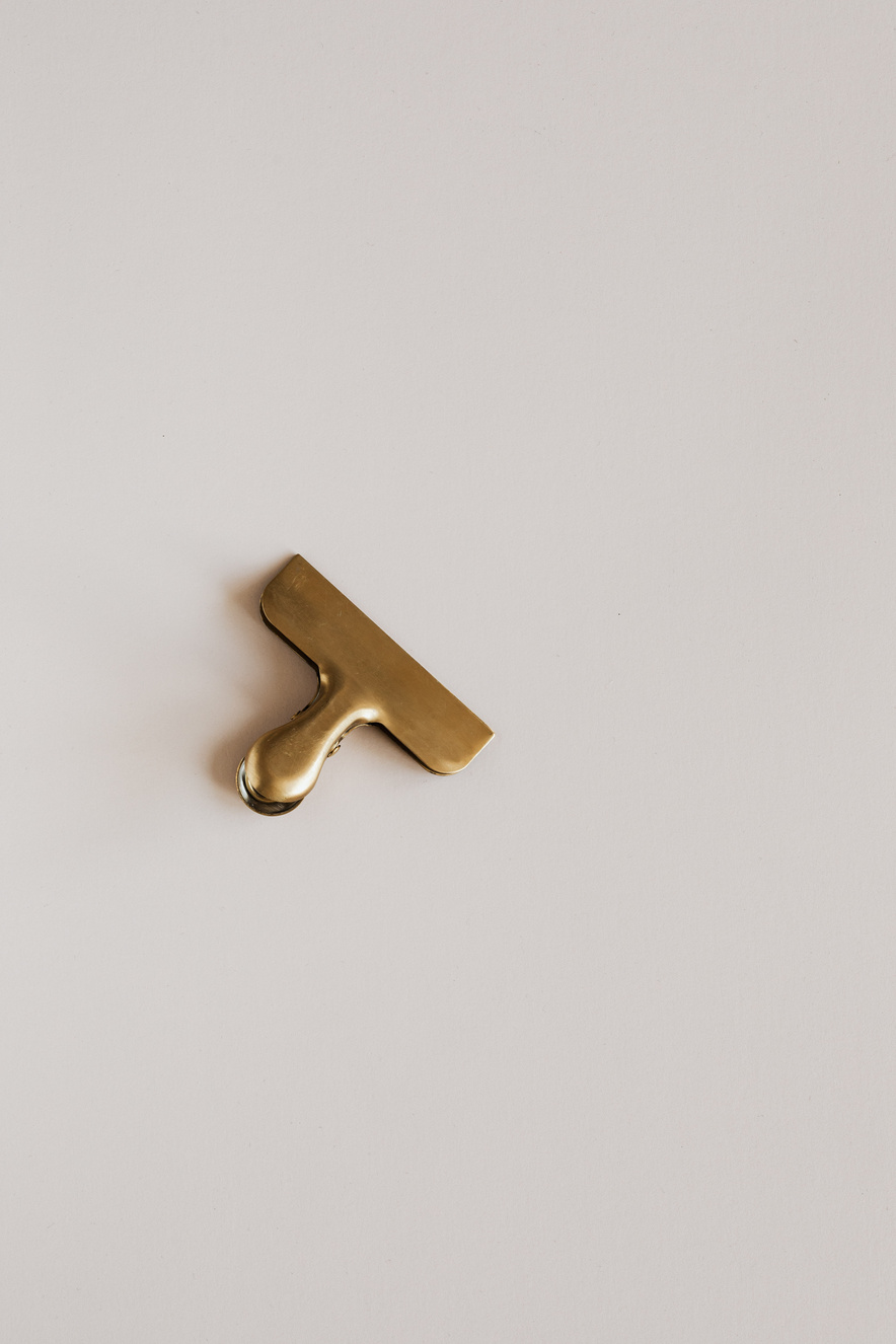 Golden clip for papers on beige table